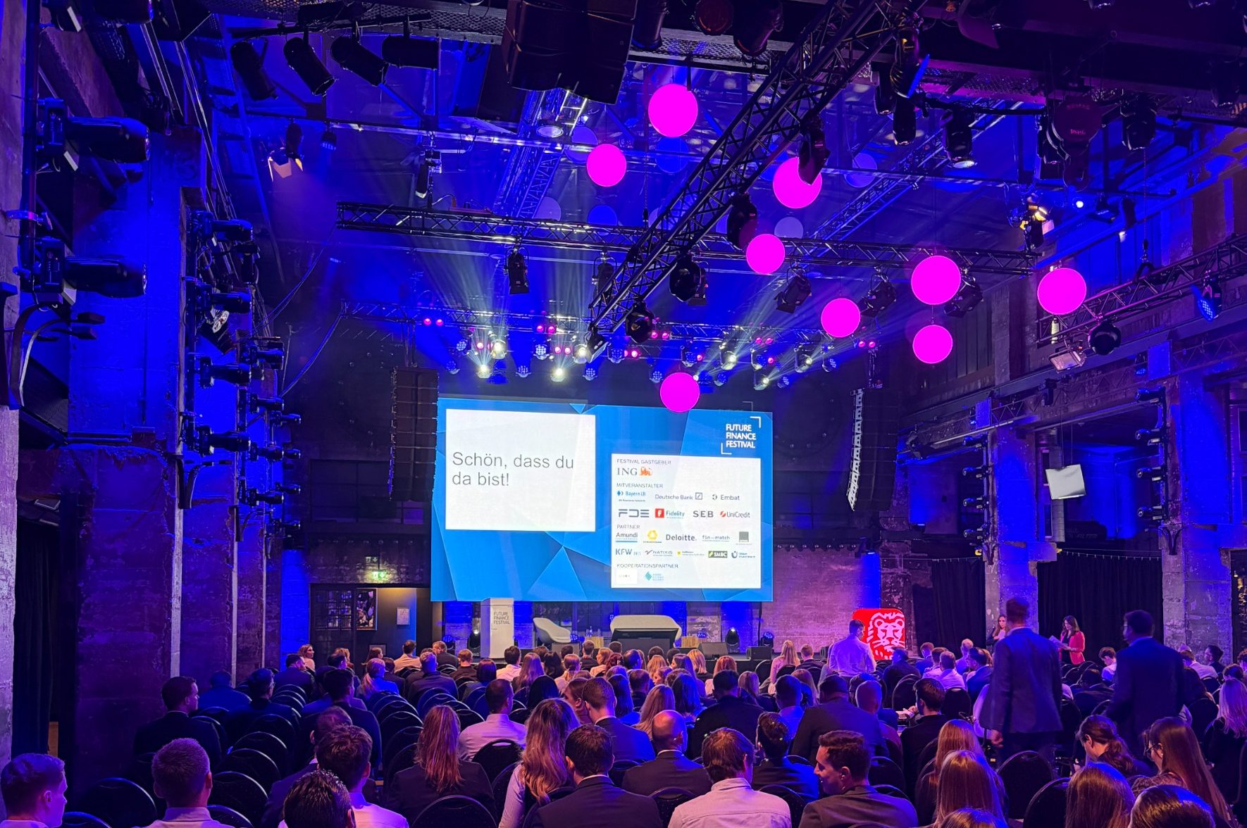 Große Konferenzbühne bei der Lucanet World 2025 mit Präsentation auf Leinwand, Redner in weißem Hemd und Publikum im Saal.